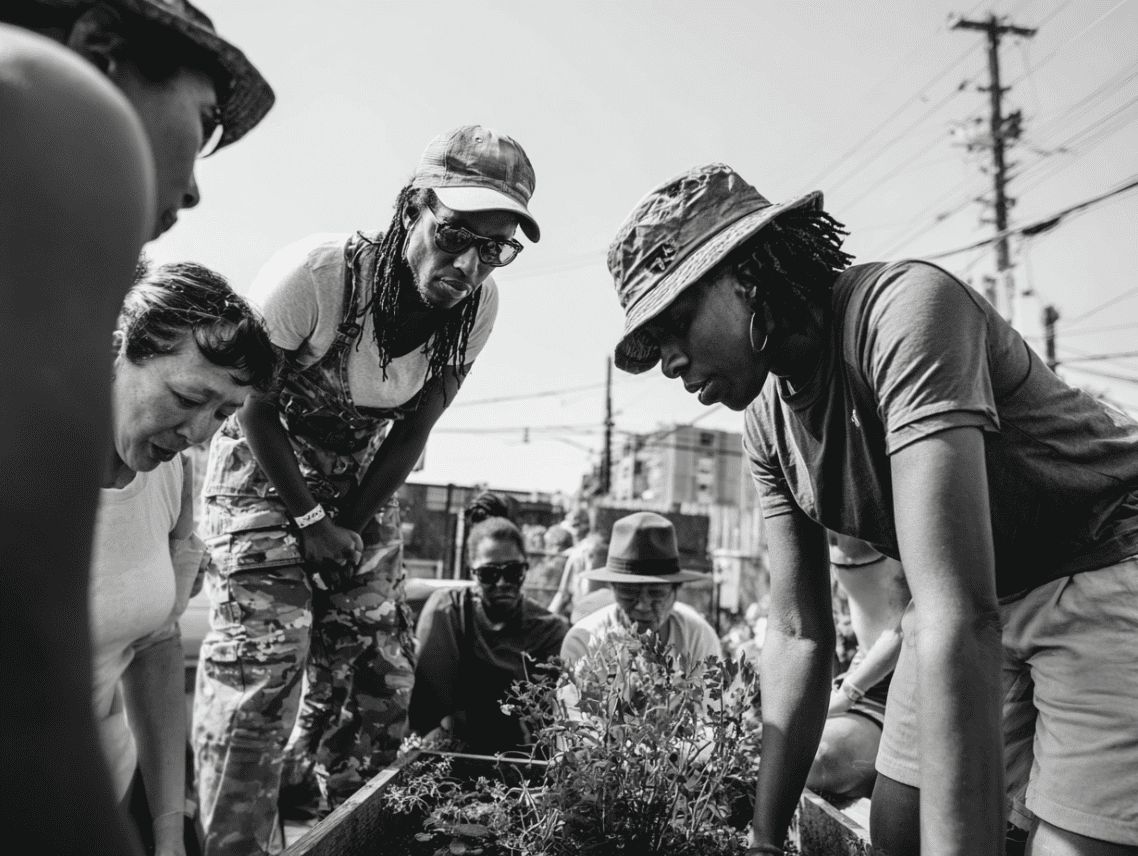 A group of community members together, learning how to garden in their neighborhood